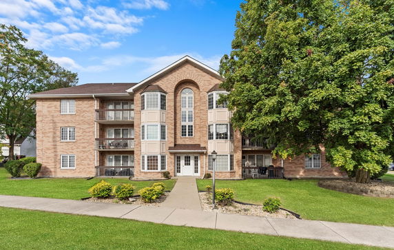 Front view of a multi-story apartment building with a central entrance and balconies.