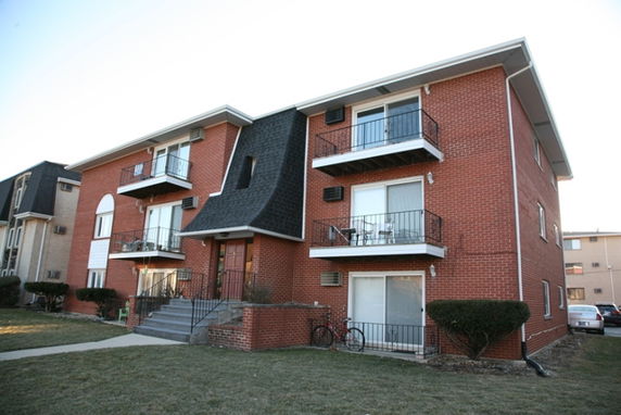 Front view of a multi-story brick apartment building with balconies.