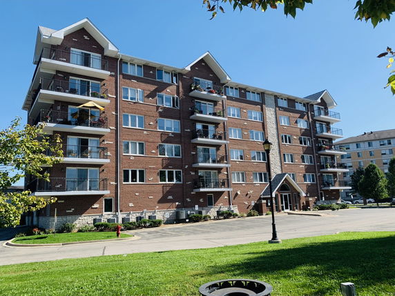 Front view of a multi-story brick apartment building with multiple balconies.