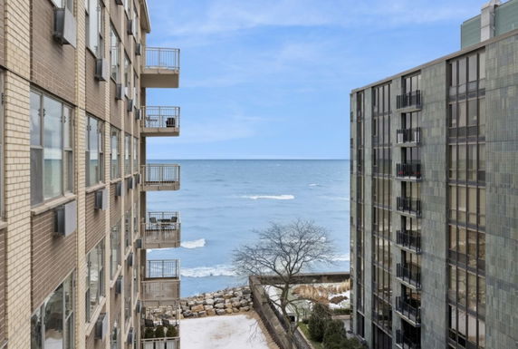 View of the ocean between two apartment buildings.
