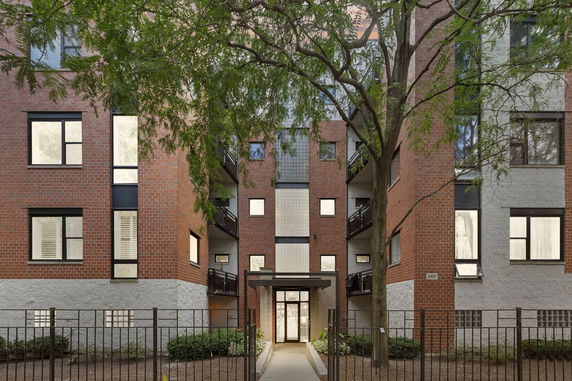 Front view of a multi-story brick apartment building with a central entrance.