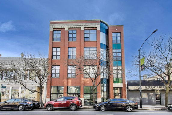 Front view of a multi-story brick building with large windows.
