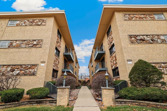 Front view of two adjacent multi-story brick buildings with balconies and stonework.
