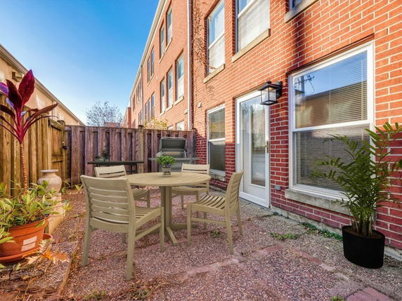 Backyard view of a multi-story brick building with a small patio area.
