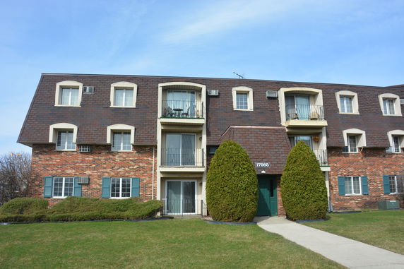 Front view of a multi-story brick apartment building with balconies.