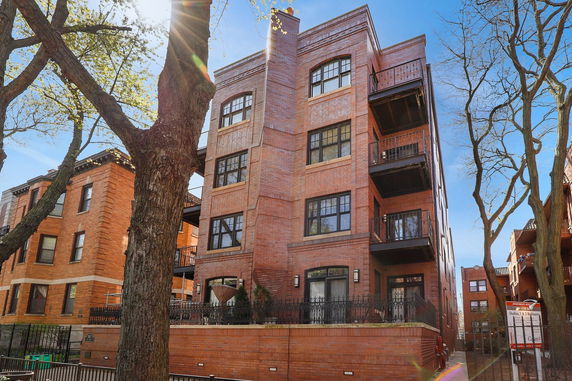 Front view of a multi-story brick apartment building with balconies.
