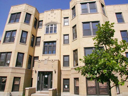 Front view of a multi-story apartment building with numerous windows and an entrance.