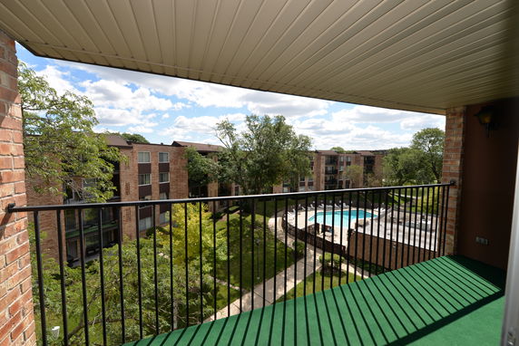 Panoramic view from a balcony overlooking apartment buildings and a swimming pool.