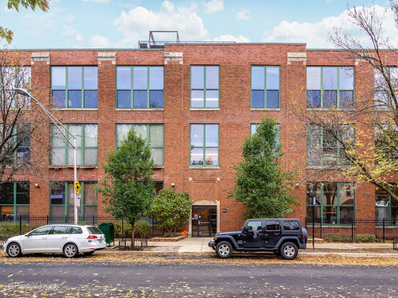 Front view of a three-story brick building with large windows.