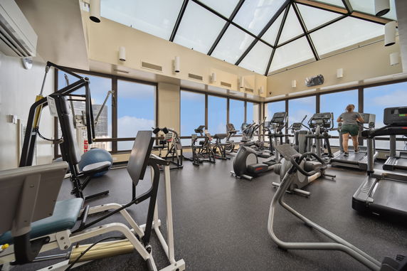 Interior view of a gym with various exercise equipment and a glass ceiling.