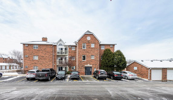 Front view of a multi-story brick building with parking spaces in front.
