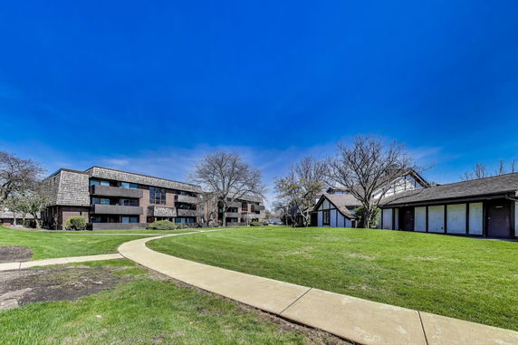 Front view of multiple residential buildings with a lawn and walkway.