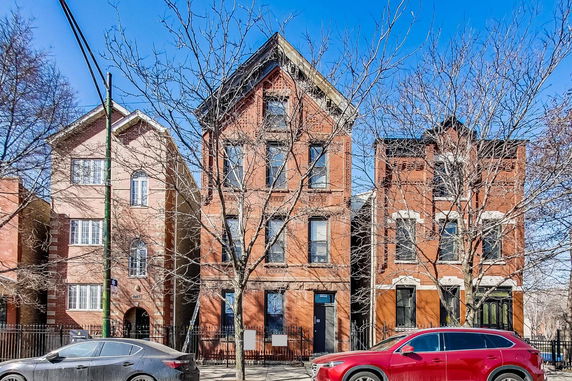 Front view of three adjacent multi-story brick houses.
