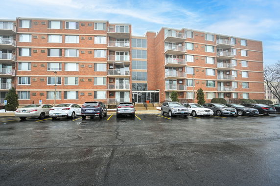 Front view of a mid-rise apartment building with brick exterior and balconies.