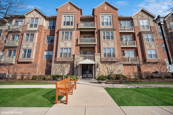 Front view of a multi-story brick apartment building with balconies.