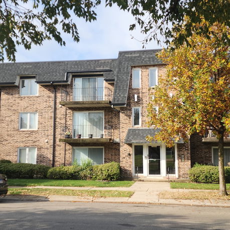 Front view of a multi-story brick apartment building with balconies.