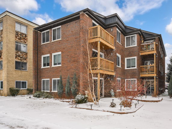 Front view of a multi-story brick apartment building with balconies.
