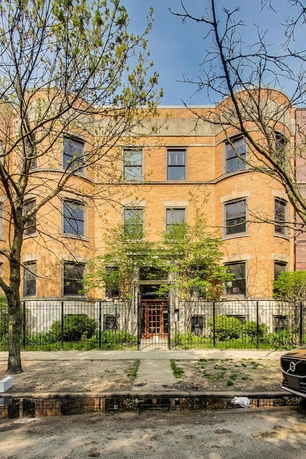 Front view of a multi-story brick building with a gated entrance.