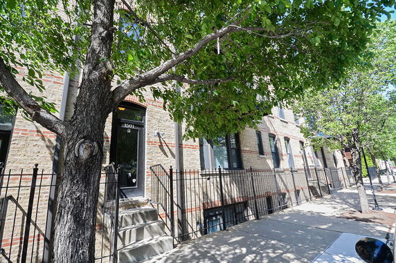 Front view of a multi-story brick building with metal railings and steps leading to entrances.