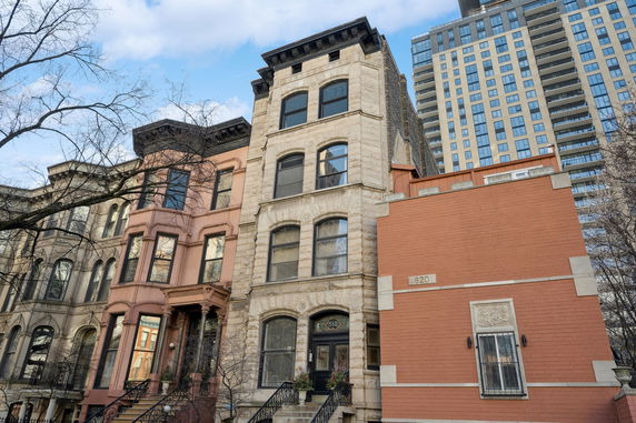 Front view of a row of multi-story historic townhouses with detailed brickwork and arched windows.