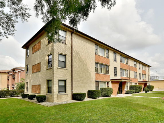 Front view of a three-story apartment building with a brick exterior.
