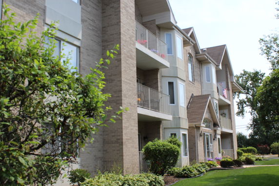 Front view of a multi-story apartment building with balconies and brick facade.