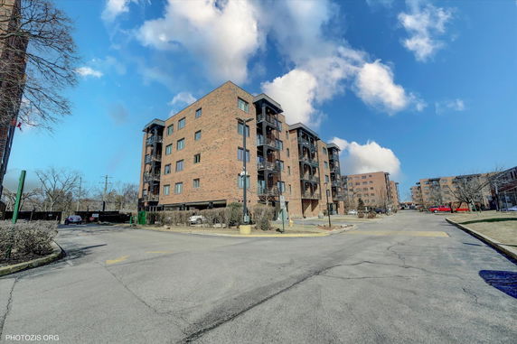 Front view of a multi-story apartment building with brick exterior and balconies.