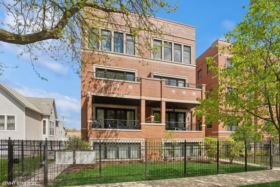 Front view of a multi-story brick building with balconies and large windows.