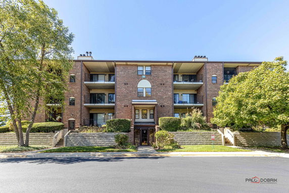 Front view of a multi-story brick apartment building with balconies.
