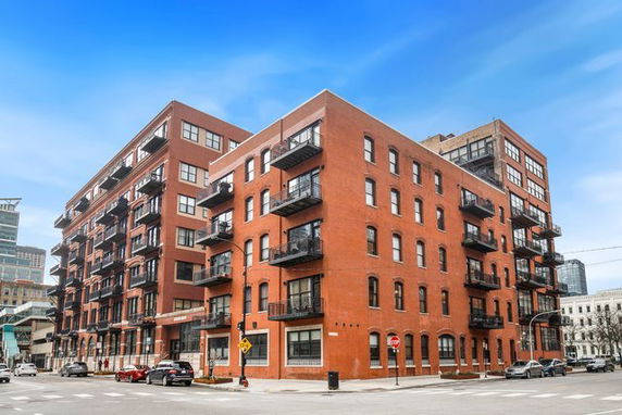Front view of a multi-story brick apartment building with balconies.