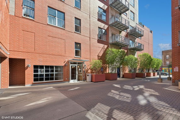 Front view of a multi-story brick building with balconies and entryway.