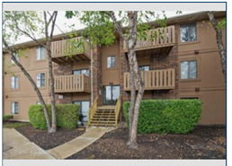 Front view of a multi-story apartment building with wooden balconies.