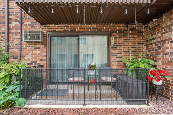 Front view of a brick building with a small balcony and decorative plants.