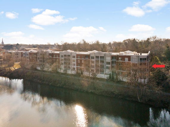 Front view of a multi-story brick and concrete building by the riverside.