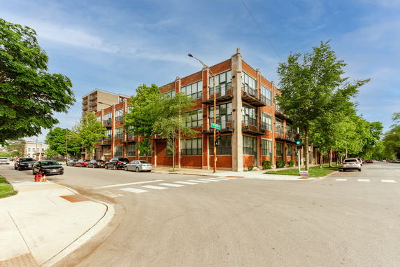 Front view of a multi-story brick building on a street corner.