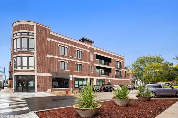 Front view of a multi-story brick building with large windows and a corner entrance.
