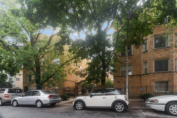 Front view of a brick apartment building with multiple windows and a gated entrance.