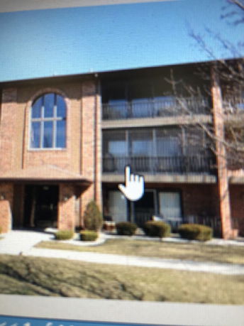 Front view of a multi-story brick building with balconies and arched windows.