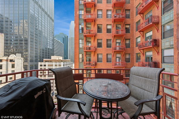 View from a balcony with outdoor furniture, overlooking a cityscape with high-rise buildings.