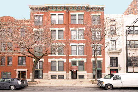 Front view of a four-story brick apartment building with large windows.