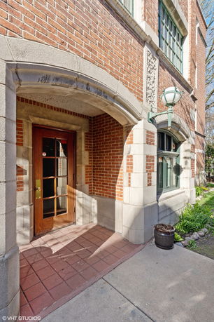 Front view of a brick building entrance with an arched doorway and decorative lamp.