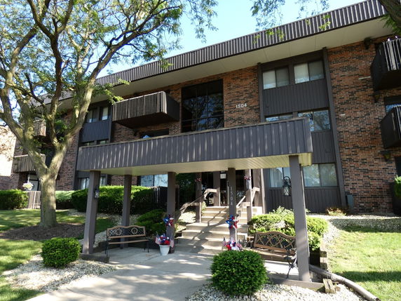 Front view of a multi-story brick apartment building with balconies.