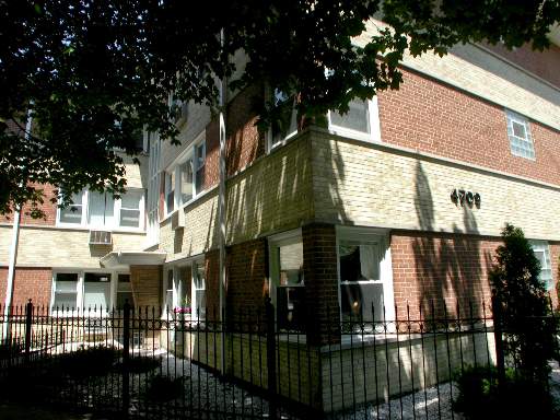 Front view of a multi-story brick building with a gated entrance.