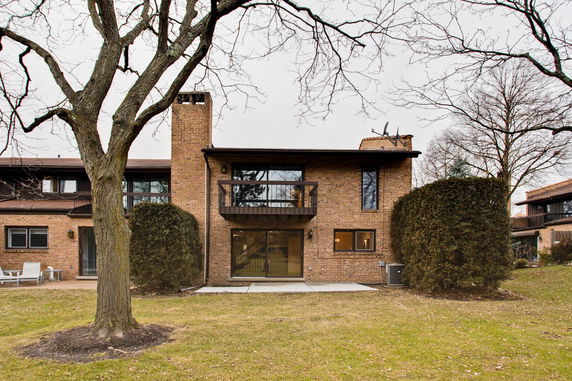 Front view of a brick house with a balcony and chimney.