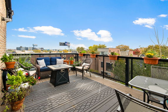 Rooftop with seating area, plants, and outdoor decor with view of surrounding buildings.