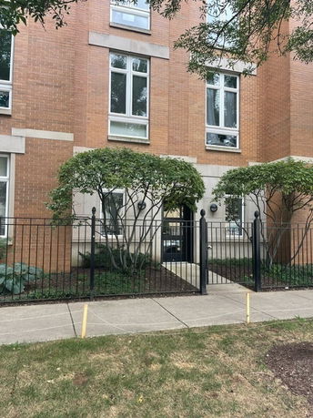 Front view of a multi-story brick building with large windows and a gated entrance.