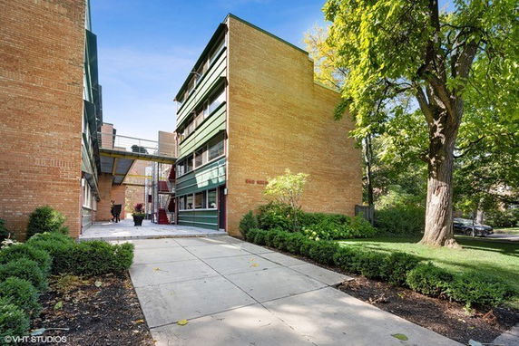 Front view of a multi-story brick apartment building with balconies and a central walkway.