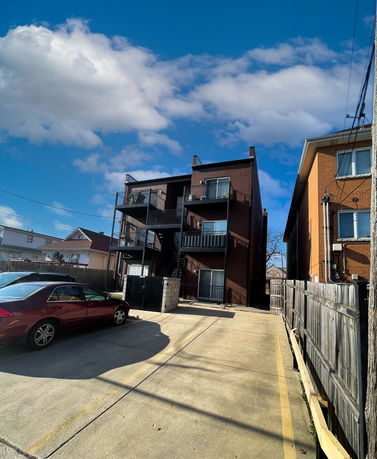 Parking area beside a multi-story brick building with balconies.