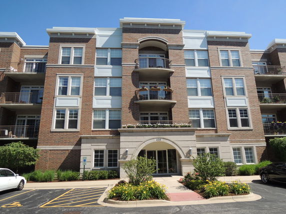 Front view of a multi-story apartment building with balconies and brick facade.