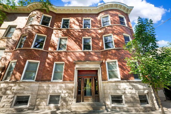 Front view of a multi-story brick building with multiple windows.